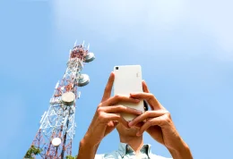Man holding a phone next to a cell tower