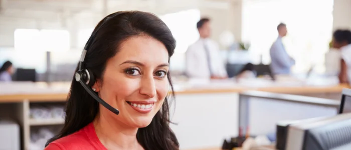 Hispanic woman working in call center smiling with headset on