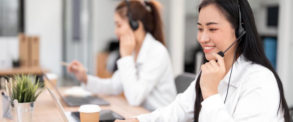 Customer support agents wearing headsets assist clients from a bright office, showing how bpo reduces employee burnout & improves workforce productivity.