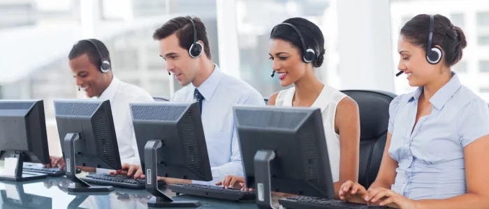 Group of call center agents smiling at computer screens