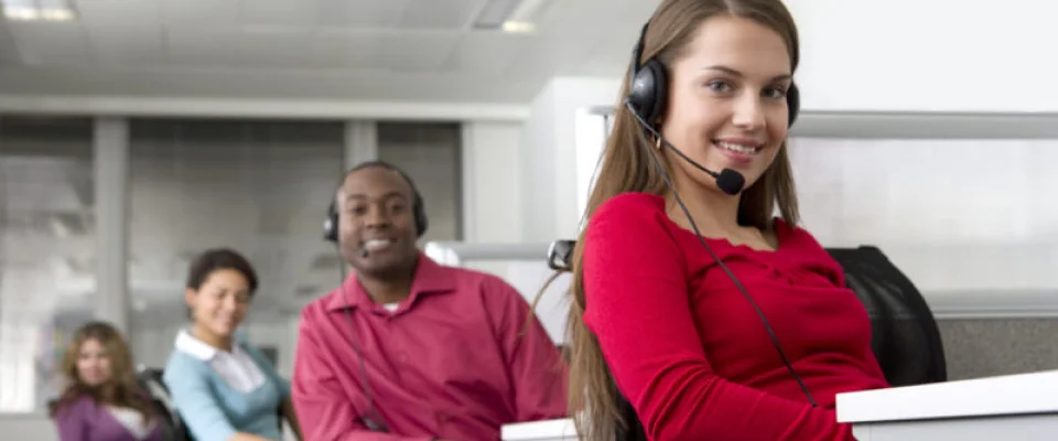 group of employees in call center smiling with headsets on