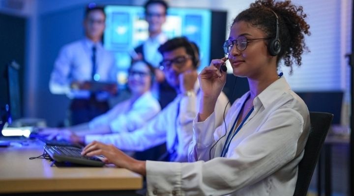 Call center agent supports customers while her team works in the background, showing the strength of a trusted call center services provider.