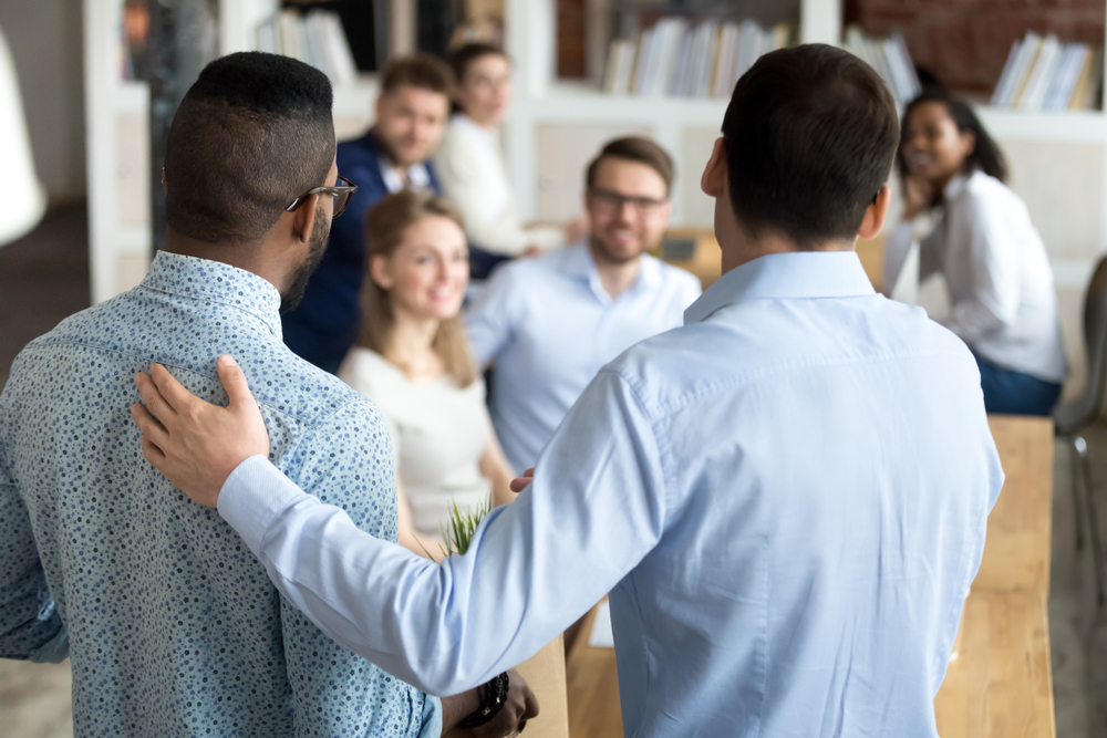 man introduces new employee to coworkers at office