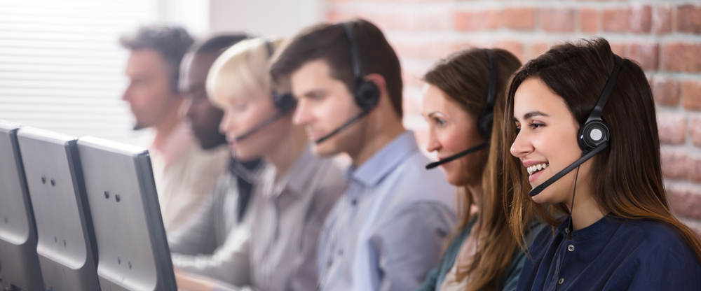 Smiling call center employees talk to customers