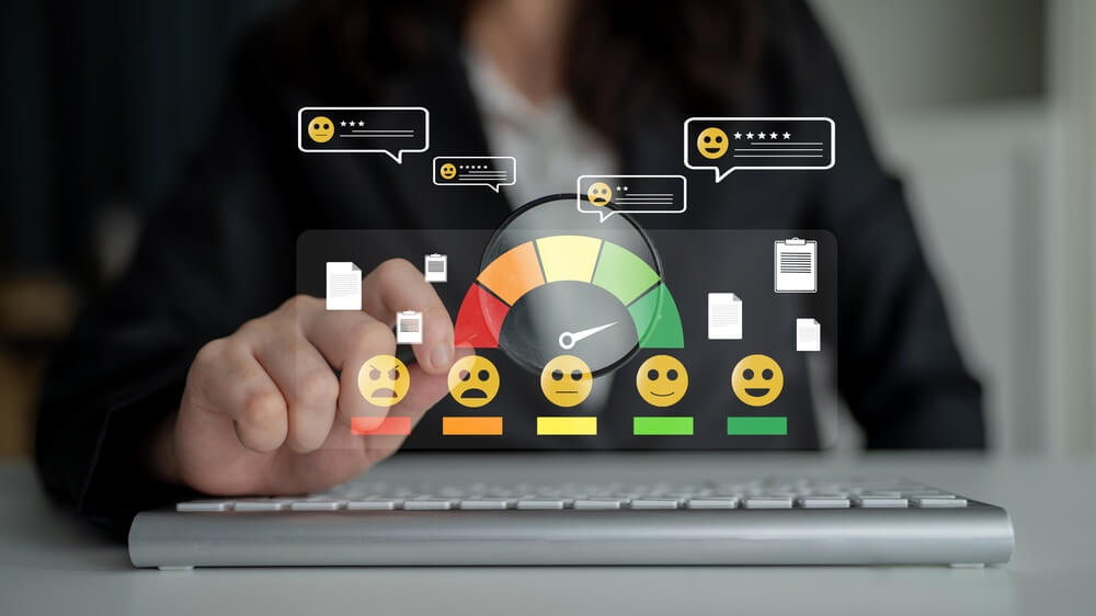 Person uses a laptop while interacting with a customer satisfaction dashboard showing emoji ratings, message bubbles, and a performance gauge, highlighting benefits of outsourcing customer support.