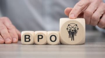 Hands arrange wooden blocks spelling “bpo” beside an icon of connected people, introducing a guide to 5 top bpo companies in the usa.