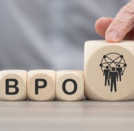 Hands arrange wooden blocks spelling “bpo” beside an icon of connected people, introducing a guide to 5 top bpo companies in the usa.