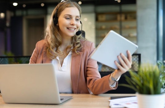 Beautiful smiling call center worker in headphones is working at modern office.