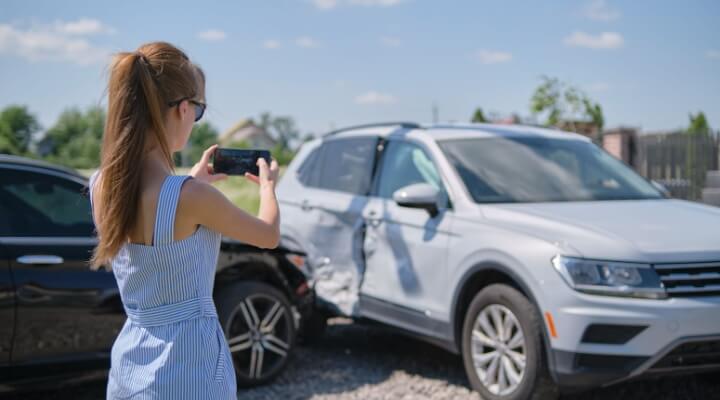 Woman taking pictures of car accident for her insurance company.