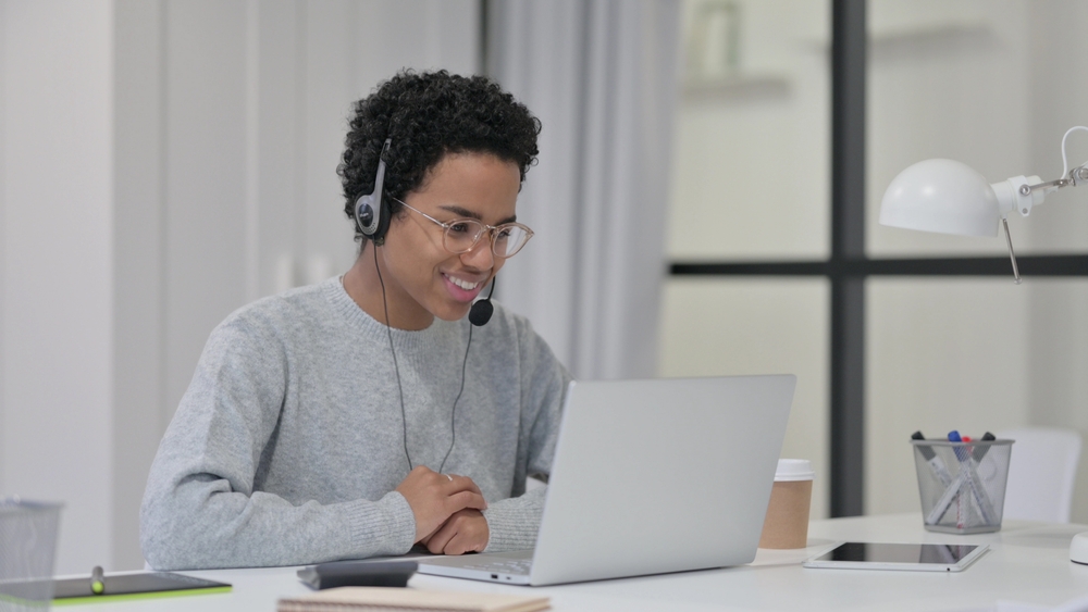 African Woman using Headset for Video Chat on Laptop