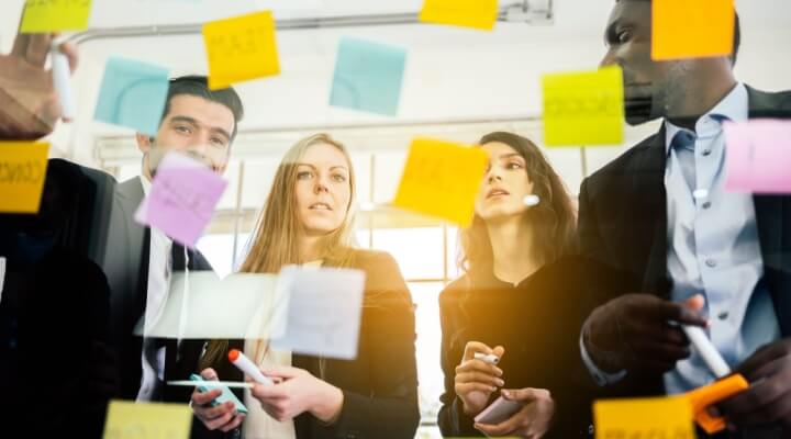 Group of successful business teamwork. Brainstorm meeting with colorful sticky paper note on glass wall for new ideas. Using agile methodology and do business. Brainstorming in a tech start-up office.