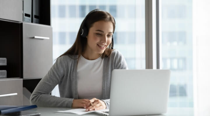 Young woman at work in call center talks to customers with headset on.