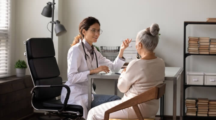 A female physician talks to a patient in her office.