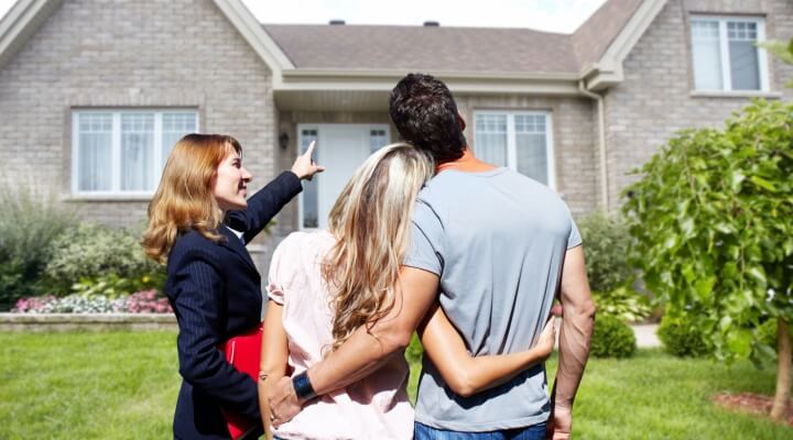 Real estate professional woman shows a home to a couple.