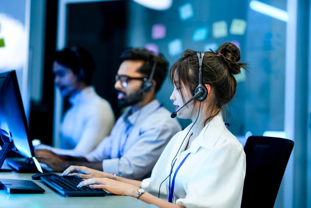 Call center agents wearing headsets work at computer stations, showing How BPO Helps Real Estate Firms Streamline client support and back-office tasks.