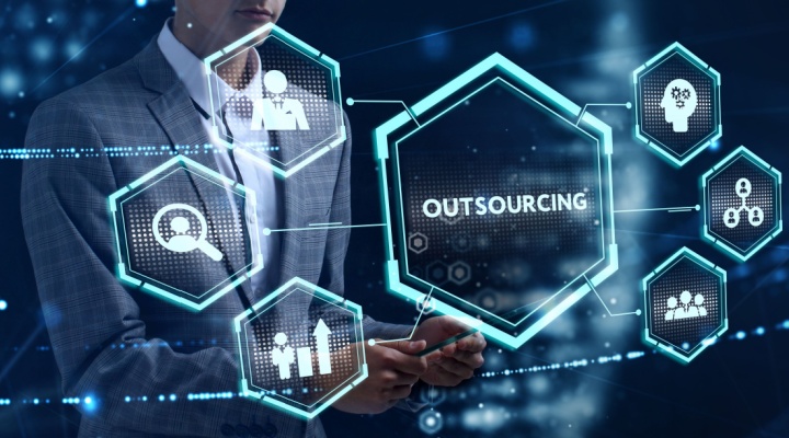 Business professional interacting with digital icons around the word outsourcing, illustrating technology-driven outsourcing trends in modern enterprises.