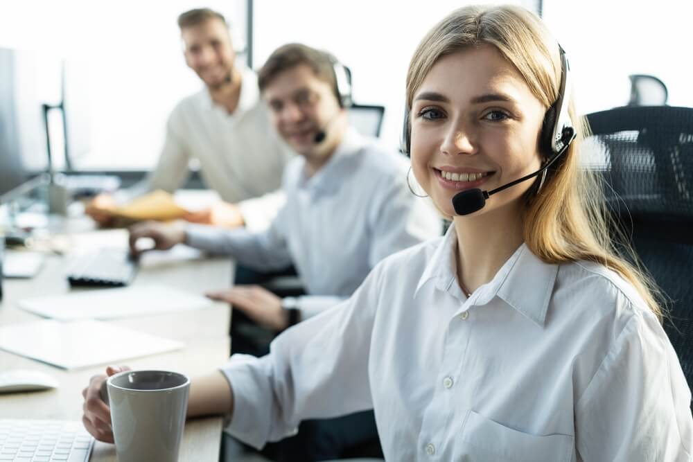 Female customer support operator with headset and smiling, providing end-of-year outsourcing cost savings to companies.