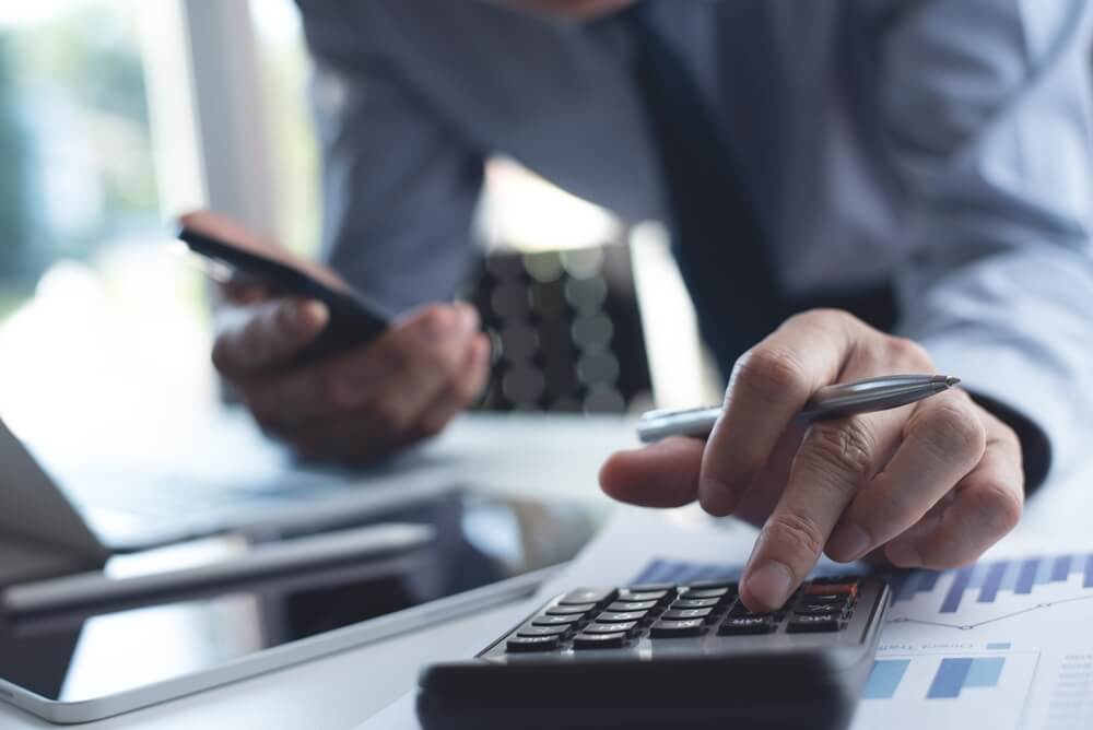 Professional using a calculator and reviewing financial documents on a desk, illustrating financial efficiency and cash flow management.
