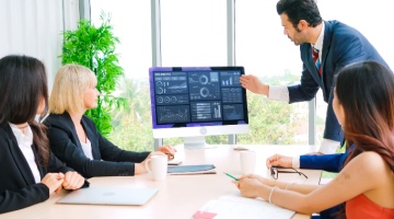 Business team reviewing analytics on a screen during a meeting, highlighting financial efficiency and data-driven decision making.