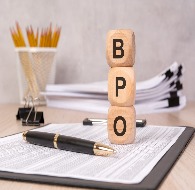 BPO business concept with wooden blocks spelling BPO on office paperwork beside a pen, pencils, and stacked documents.