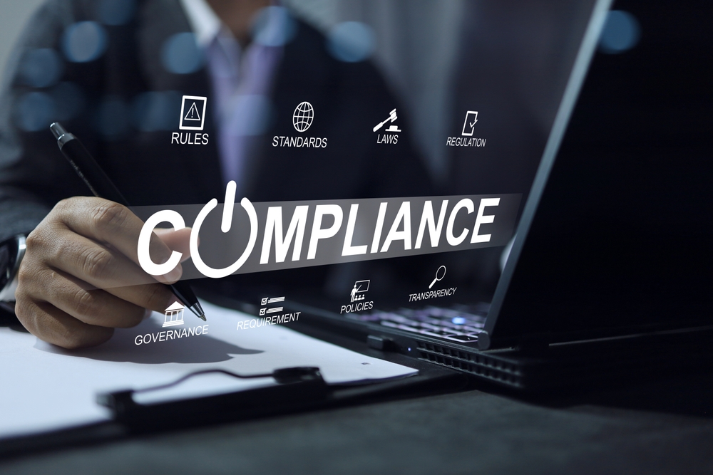 Business professional working on a laptop with a digital compliance interface displaying governance, policies, standards, laws, regulations, transparency, and requirements, representing BPO compliance and regulatory management.
