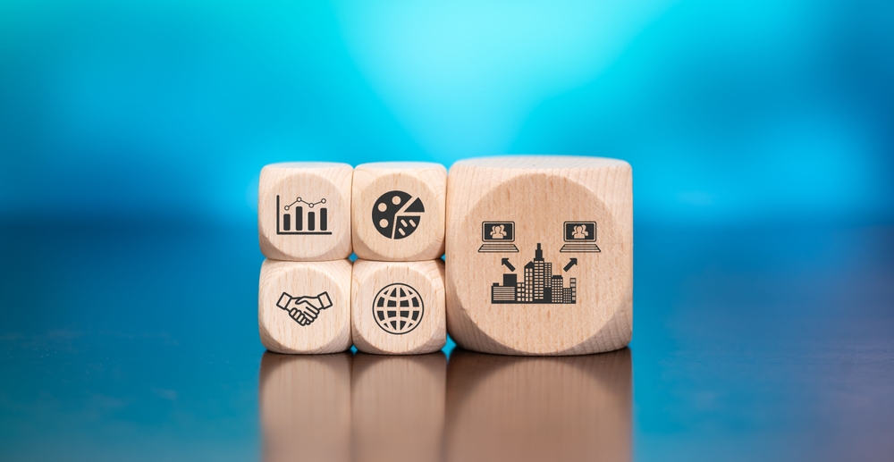 Wooden blocks with icons representing analytics, collaboration, global business, and outsourcing surrounding a larger block with connected office buildings, illustrating BPO services, business growth, and operational efficiency.