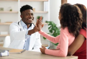 Two patients shaking hands with a male doctor.