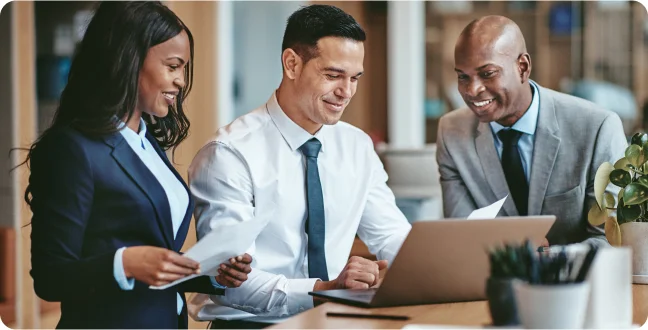 Three coworkers looking at a laptop