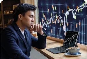 Sitting man looking at a laptop screen with finance charts.