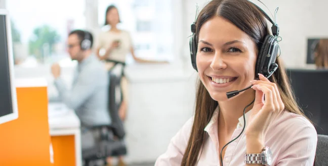 Female call center agent with headsets while smiling.