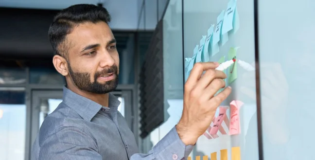 Side view of a businessman writing on a whiteboard.