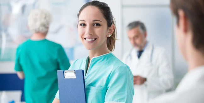 Female nurse holding patient records while smiling in a hospital.