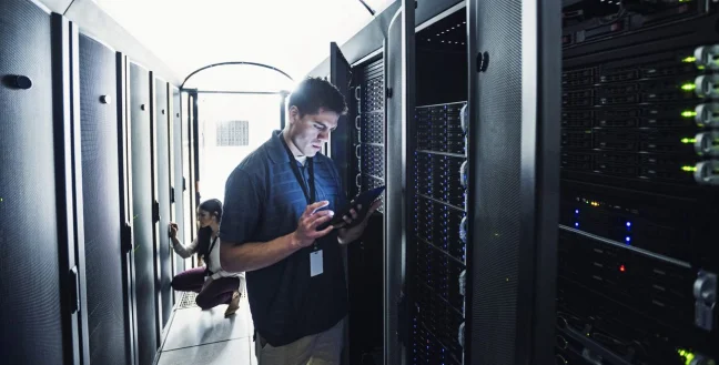 Technician man in a server room with an Ipad.