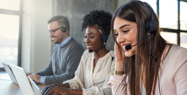 Three call center agents smiling.