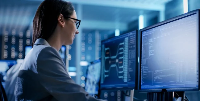 Female engineer looking at data of two monitors.